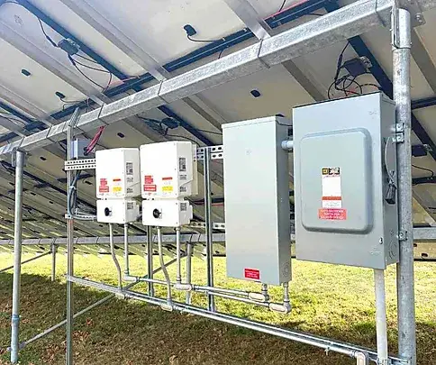 Close-up of inverter and electrical components beneath a ground mount solar panel system installed by Premier Improvements Solar in Connecticut.