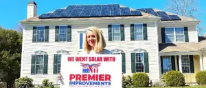 Premier Improvements Solar customer smiling proudly in front of new home solar panel installation in Connecticut.